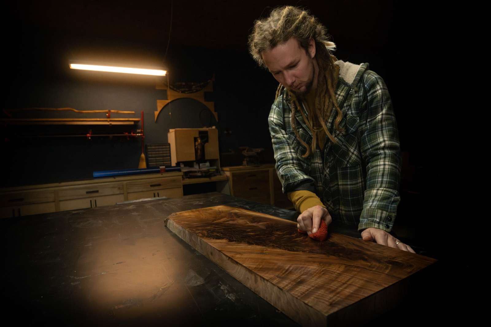 Raccoon Mountain Woodworks craftsman finishing a live-edge slab in the workshop