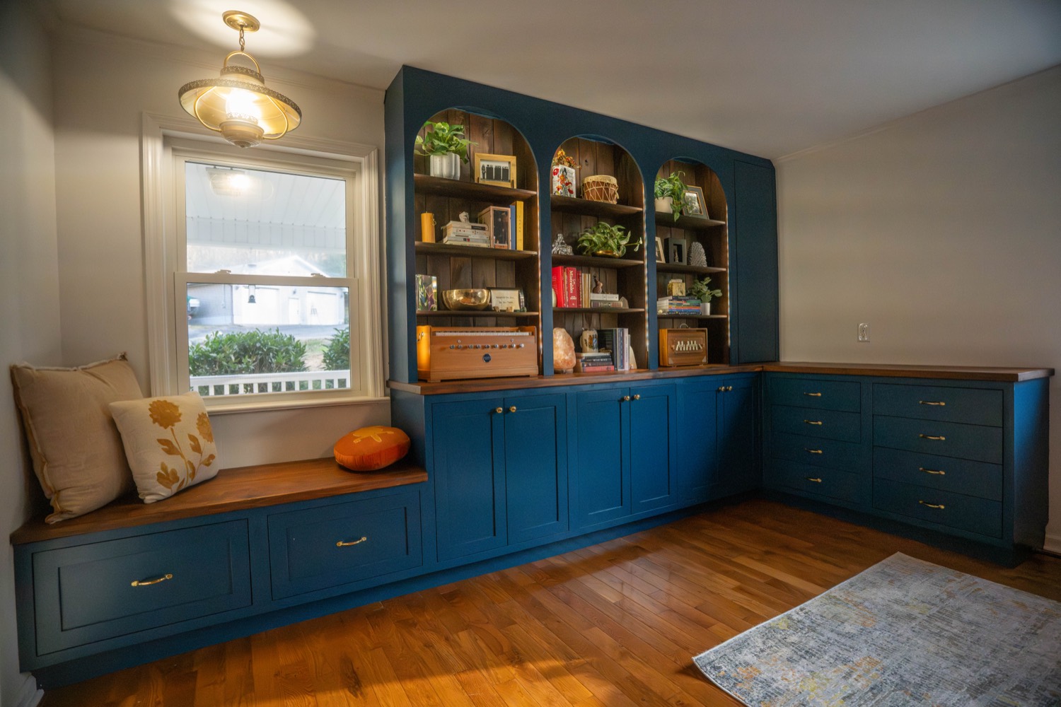 Navy built-in cabinetry with arched shelving, window bench seating, and drawers