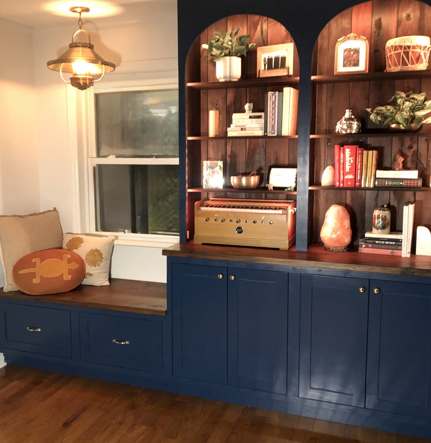 Navy built-in cabinetry with arched shelving and a window bench seat