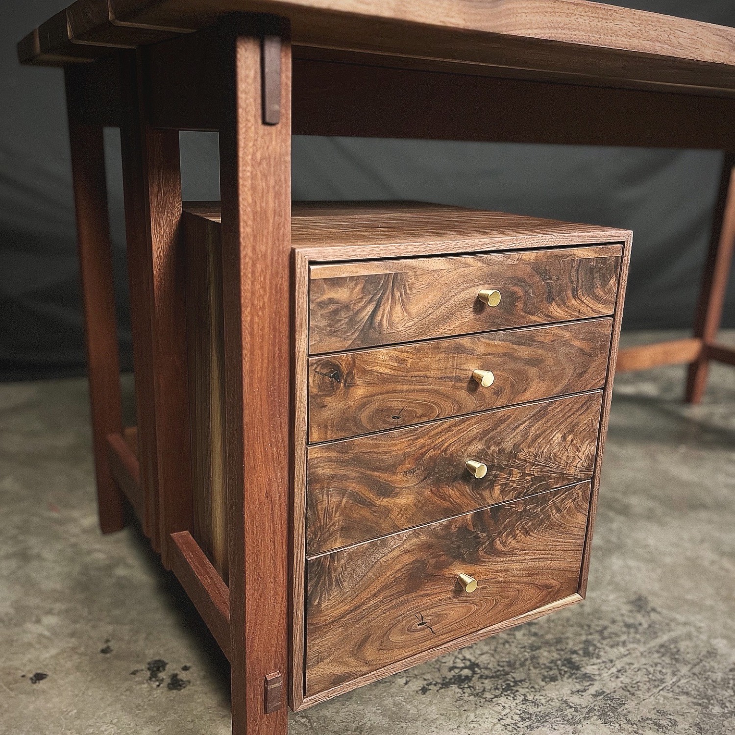 Close-up of figured walnut desk drawers with brass knobs