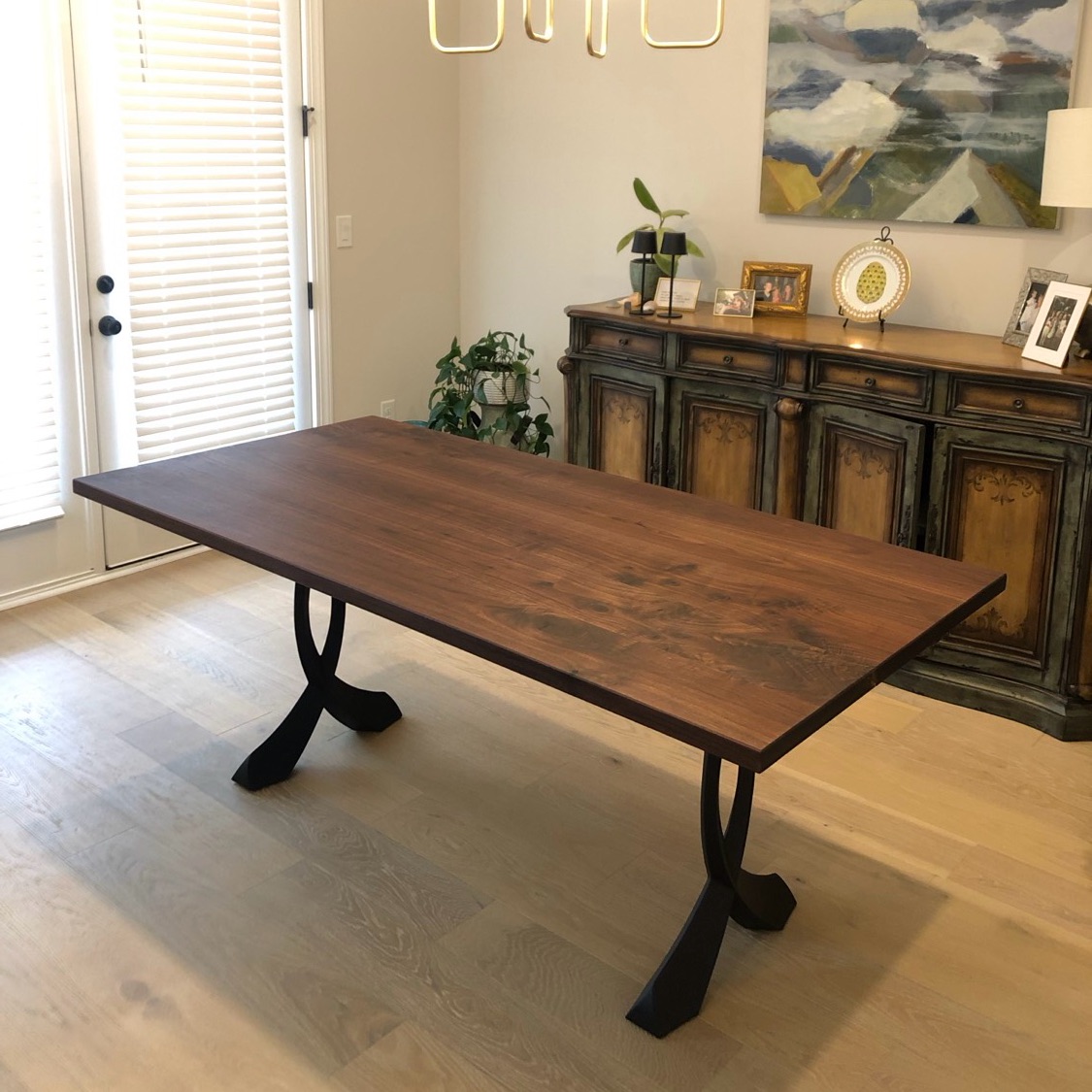 Walnut dining table with sculpted metal legs in a dining room
